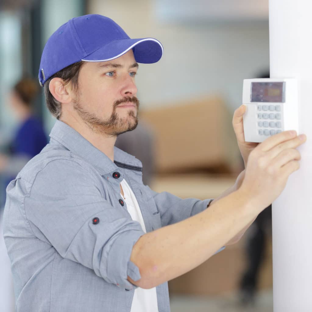 man installing alarm system indoors
