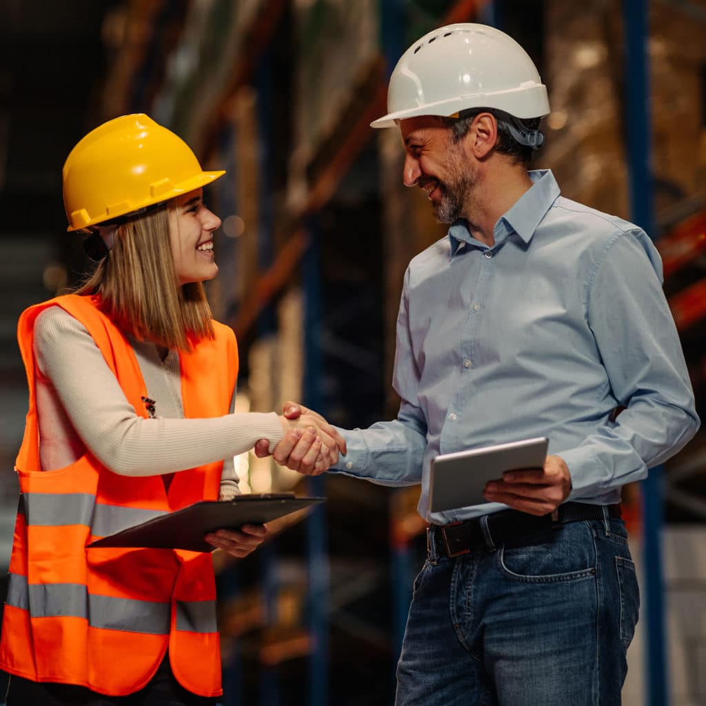 Two people shaking hands in a large warehouse